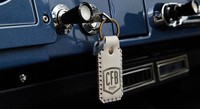 Leather keychain with CFB Series logo hanging from a blue dashboard key slot