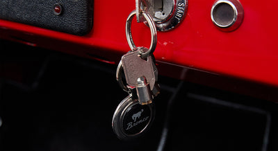 Ignition key inserted in red dashboard, attached to keychain with Bronco logo
