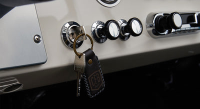 Metal key inserted in ignition with attached leather keychain embossed with CFB logo inside Classic Ford Bronco.