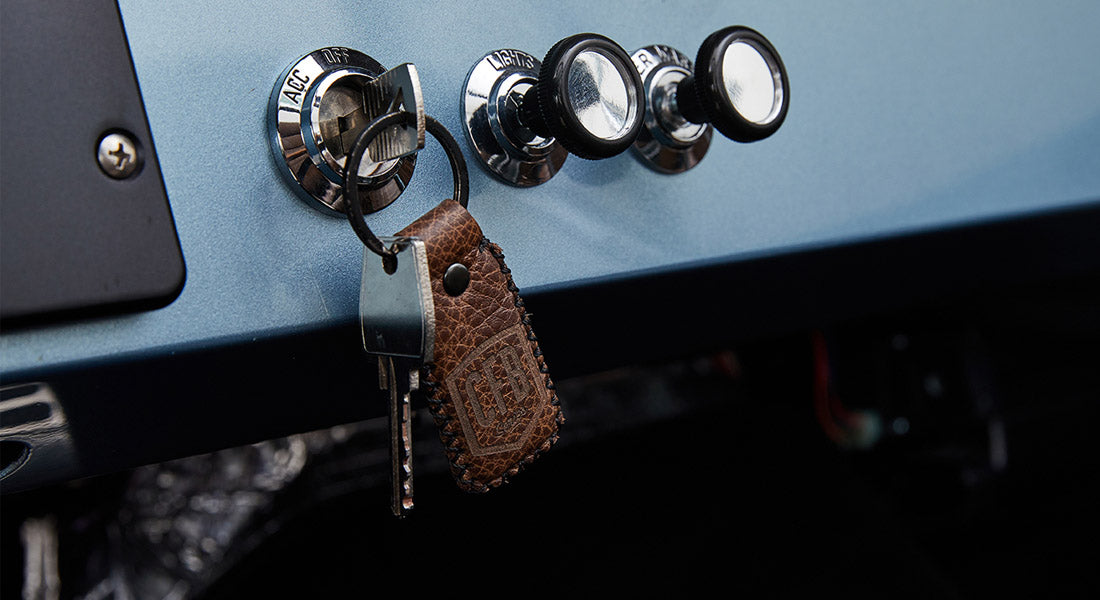 Ford Bronco key in ignition with a brown leather keychain hanging on a light blue dashboard panel