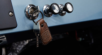 Ford Bronco key in ignition with a brown leather keychain hanging on a light blue dashboard panel