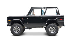 Black Classic Ford Bronco side view with lifted wheels and roll cage, blue plaid seats visible