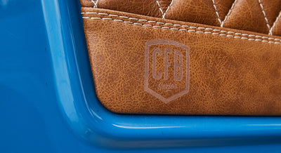 Close-up of laser-etched logo on brown leather upholstery of Classic Ford Bronco with blue exterior paint