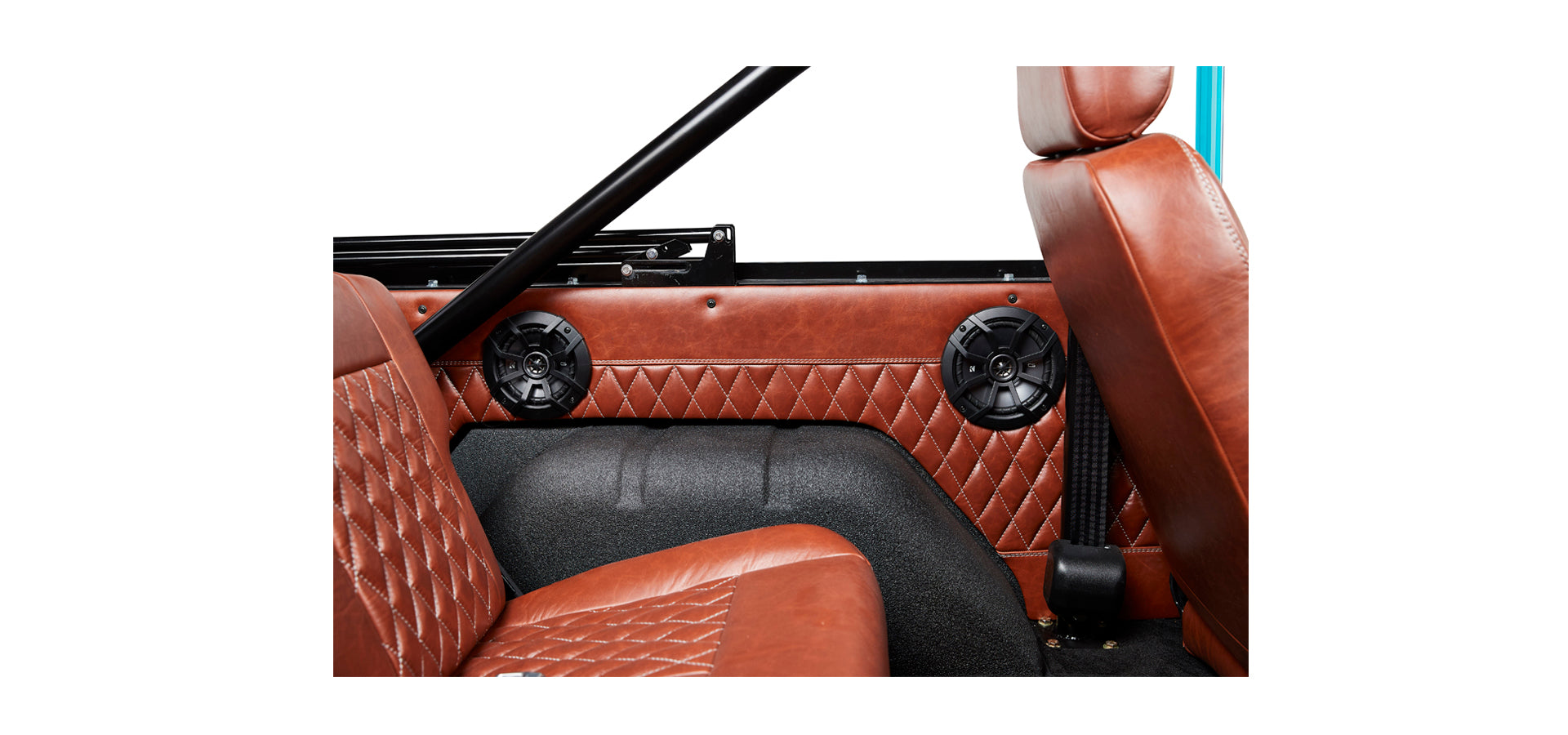 Interior view of Classic Ford Bronco brown leather seats and quilted door panel with black speaker grilles