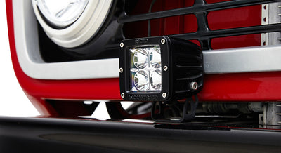 Black rectangular LED off-road light mounted on red front bumper of Classic Ford Bronco.
