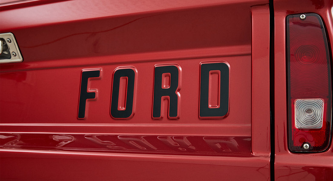 Red tailgate panel of Classic Ford Bronco with large black raised FORD letters and tail light