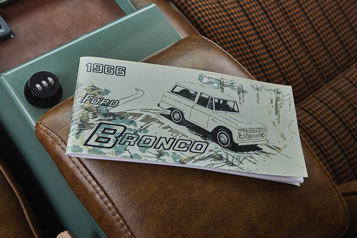 1966 Ford Bronco manual booklet on a brown leather seat in Classic Ford Bronco interior