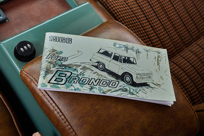 1966 Ford Bronco manual booklet on a brown leather seat in Classic Ford Bronco interior