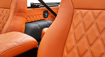 Close-up of orange diamond-stitched leather seats inside Classic Ford Bronco