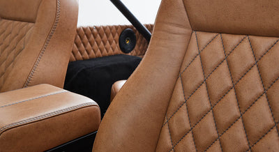 Tan leather seats and diamond-stitched leather panel with black speaker in interior of Classic Ford Bronco