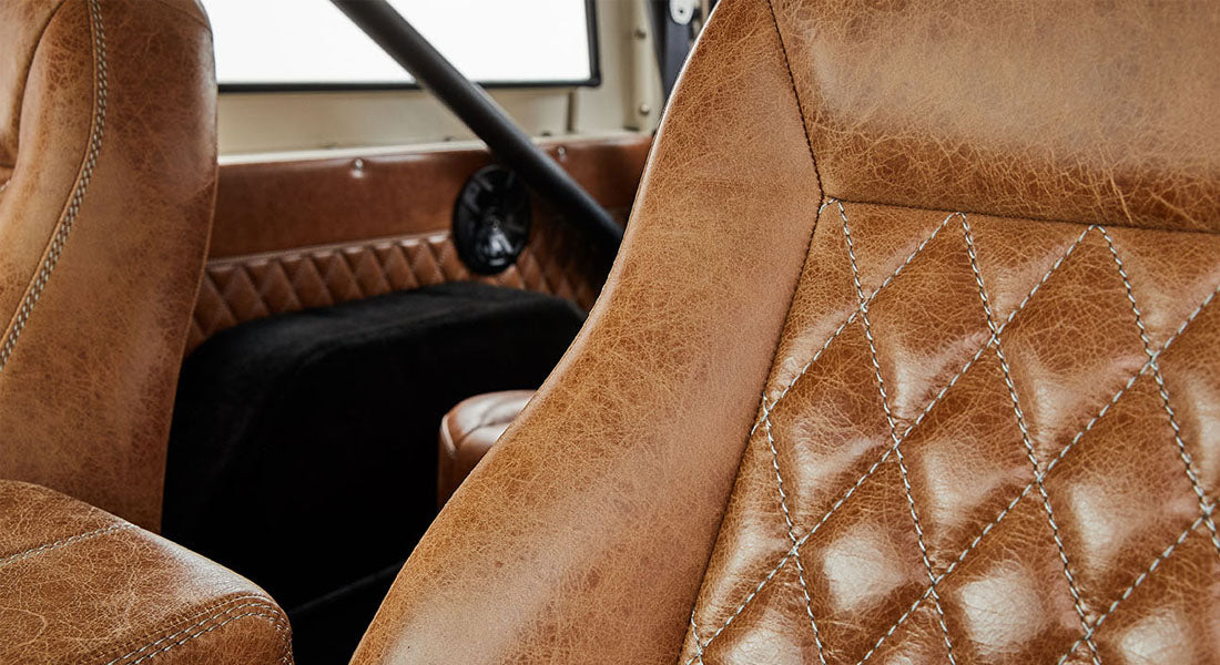 Close-up of tan leather seats and door panel with diamond stitching inside a vehicle.