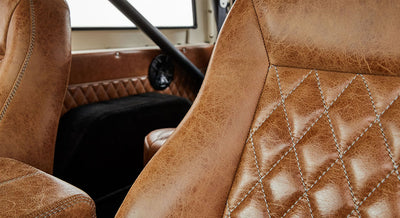 Close-up of tan leather seats and door panel with diamond stitching inside a vehicle.