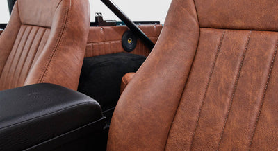 Brown leather seat and armrest inside Classic Ford Bronco with round speaker in background