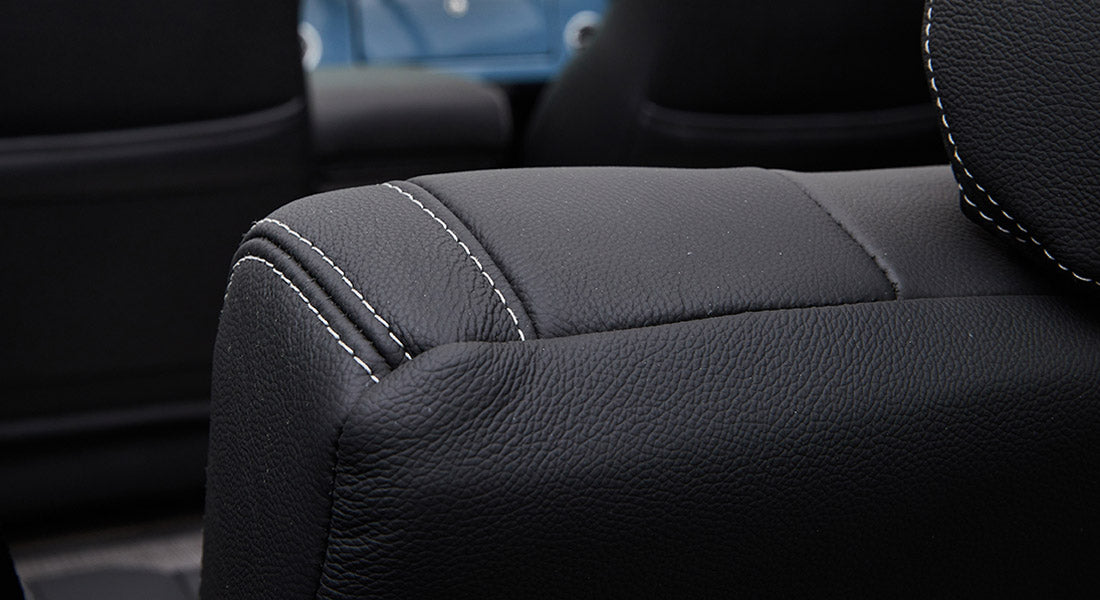 Close-up of black leather upholstery with white stitching inside classic Ford Bronco