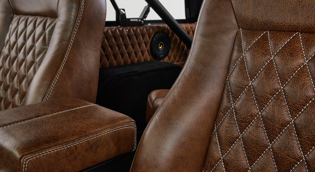 Brown diamond-stitched leather car seats with white stitching and speaker in rear side panel