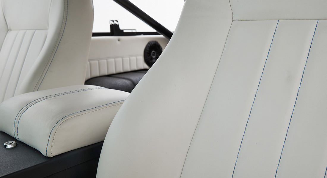 White leather car seats with blue stitching inside Classic Ford Bronco interior.