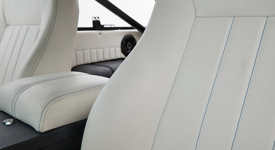 White leather car seats with blue stitching inside Classic Ford Bronco interior.