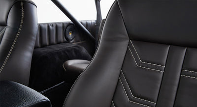 Interior seats of a Classic Ford Bronco in black with white stitching and rear speaker