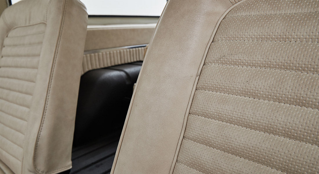 Textured beige seat upholstery and black armrest in Classic Ford Bronco interior