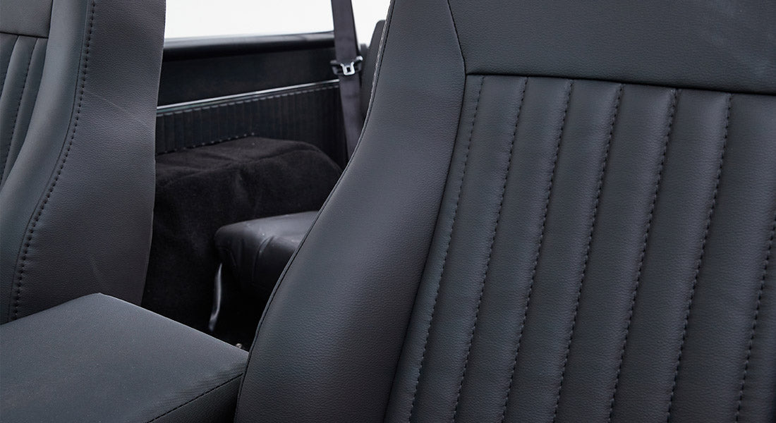 Back seat of Classic Ford Bronco with black leather upholstery and vertical stitching