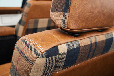Close-up of brown leather and plaid fabric seat detail in Classic Ford Bronco