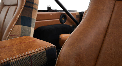 Close-up of car seat and armrest with brown leather and plaid fabric