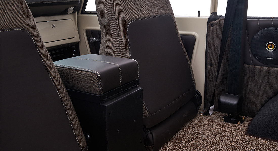 Rear view of two brown fabric and leather seats inside Classic Ford Bronco with speaker visible