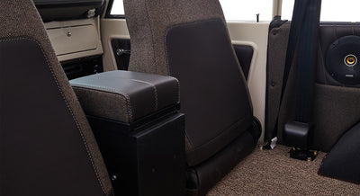 Rear view of two brown fabric and leather seats inside Classic Ford Bronco with speaker visible