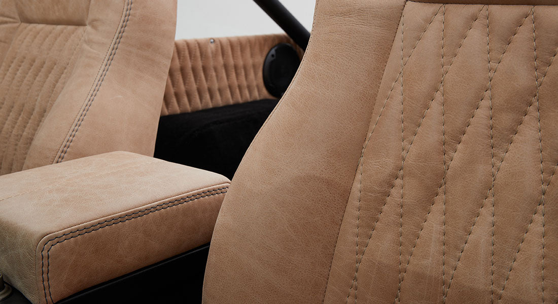 Side view of tan leathery classic car seats with detailed stitching in a Classic Ford Bronco
