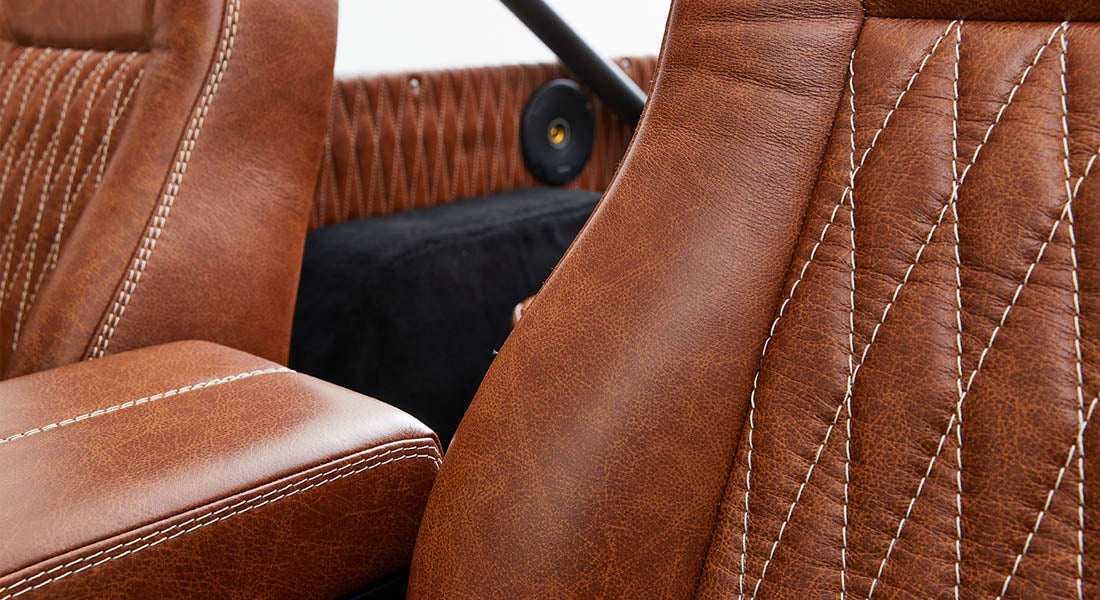 Brown leather car seats with detailed white stitching inside a Classic Ford Bronco