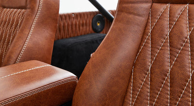 Brown leather car seats with detailed white stitching inside a Classic Ford Bronco