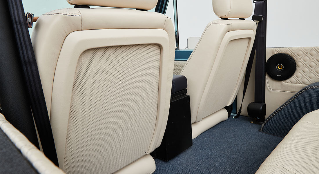 Beige leather rear seats and quilted door panel inside a Classic Ford Bronco