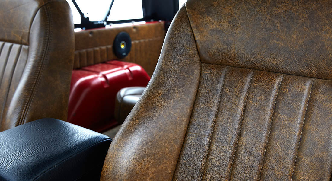 Brown leather seat interior detail in Classic Ford Bronco with visible stitching and red metal body