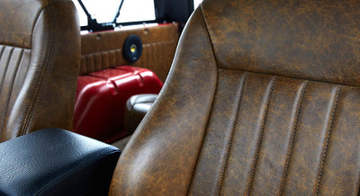 Brown leather seat interior detail in Classic Ford Bronco with visible stitching and red metal body