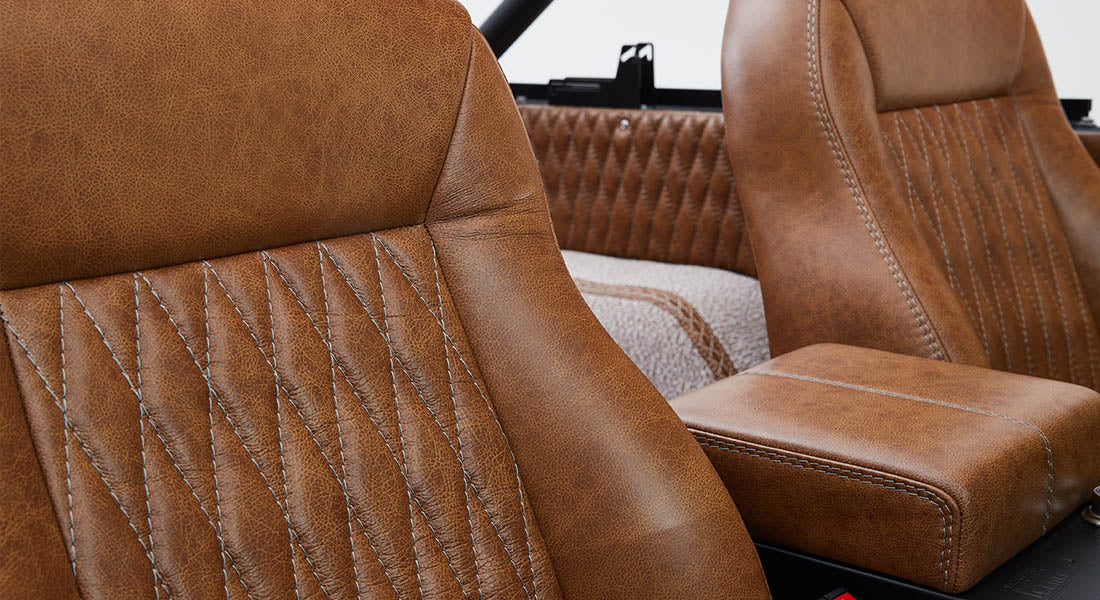 Pair of brown leather car seats with white stitching and center console inside Classic Ford Bronco