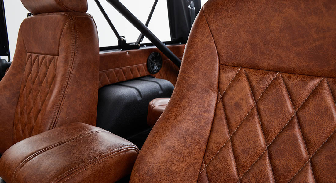 Classic Ford Bronco backseat interior with tan leather seats, diamond stitching, and black roll cage