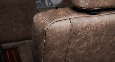 Close-up view of worn brown leather seat corner with white stitching