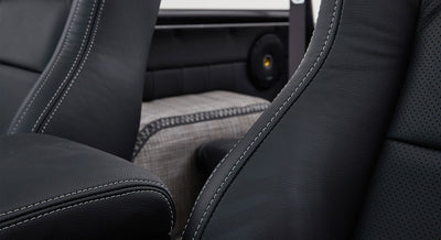 Side view of black leather seats with white stitching and patterned fabric insert in classic Ford Bronco interior