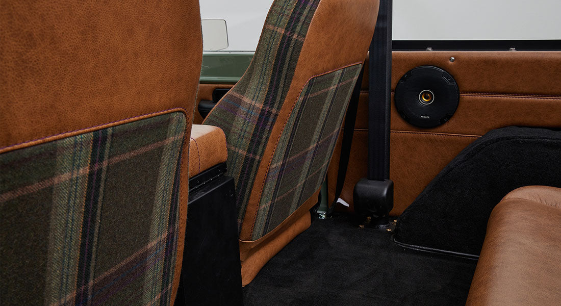 Rear view of brown leather and plaid fabric seats inside Classic Ford Bronco