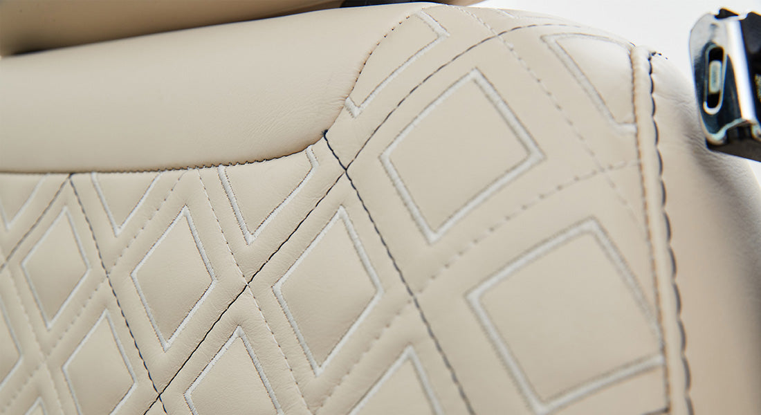 Detailed view of stitched beige leather upholstery with diamond pattern on Classic Ford Bronco seat