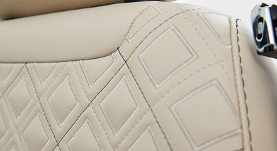 Detailed view of stitched beige leather upholstery with diamond pattern on Classic Ford Bronco seat