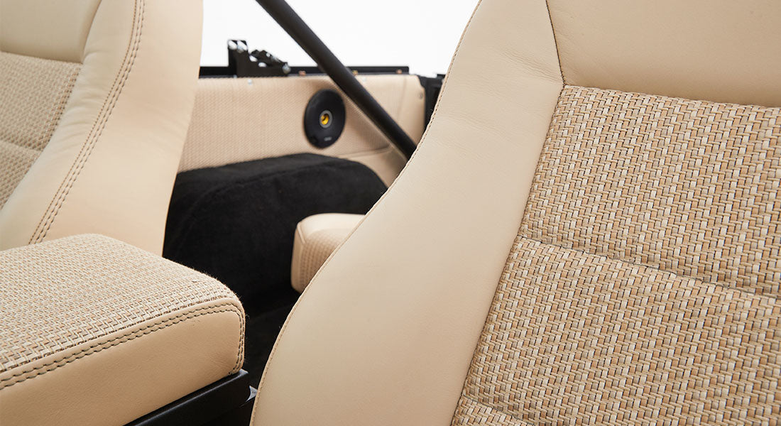 Close-up of beige and tan textured fabric vehicle seats with black stitching detail