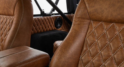 Brown leather seats and quilted interior panel inside Classic Ford Bronco with black speaker