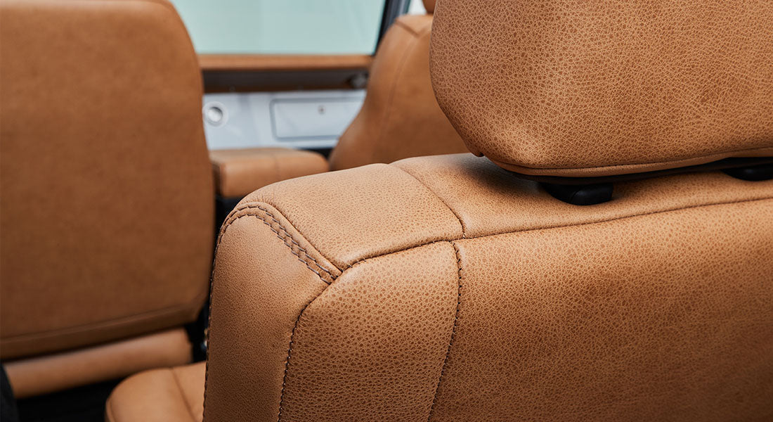Close-up of tan leather upholstery with detailed stitching inside a Classic Ford Bronco.