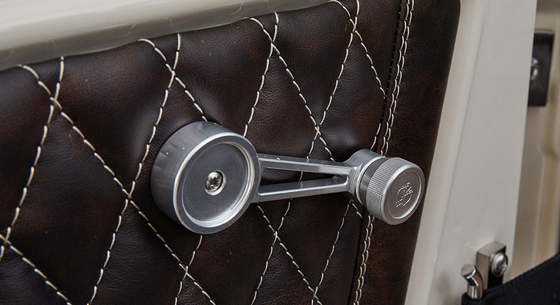 Diamond-stitched brown leather door panel with metal window crank handle in Classic Ford Bronco