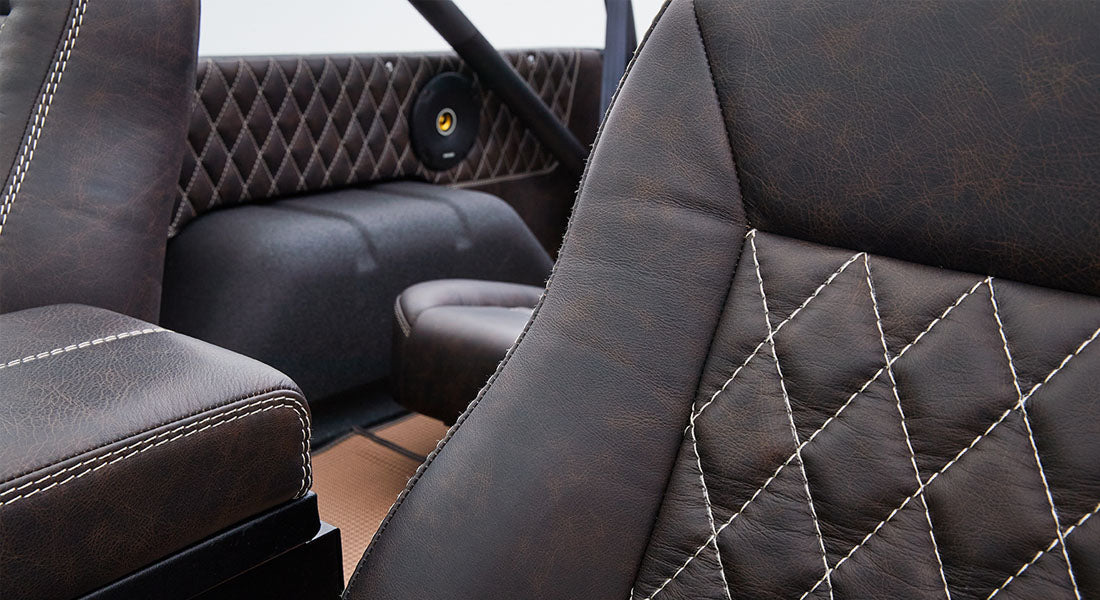 Interior close-up of diamond-stitched brown leather seats in a Classic Ford Bronco