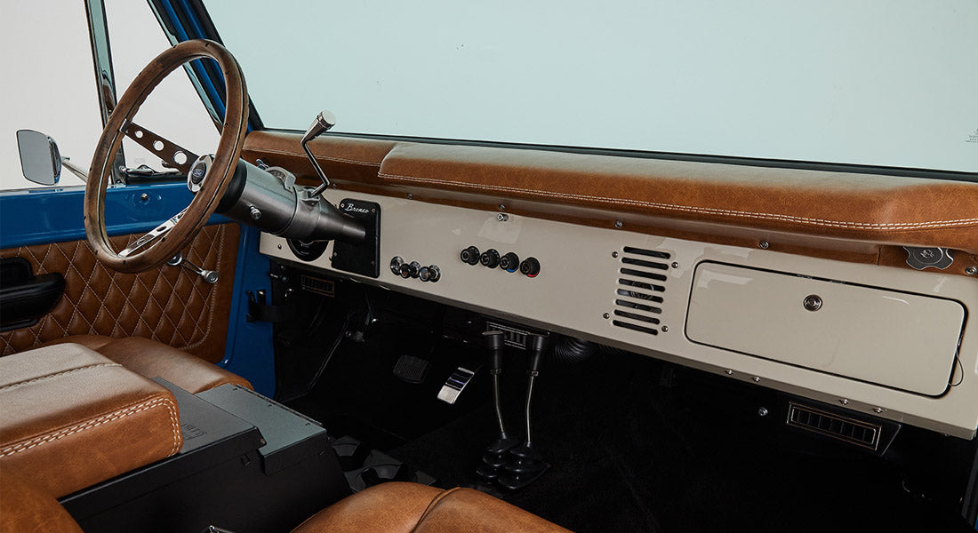 1976 Blue Classic Ford Bronco Coyote Series with black soft top and whiskey leather interior