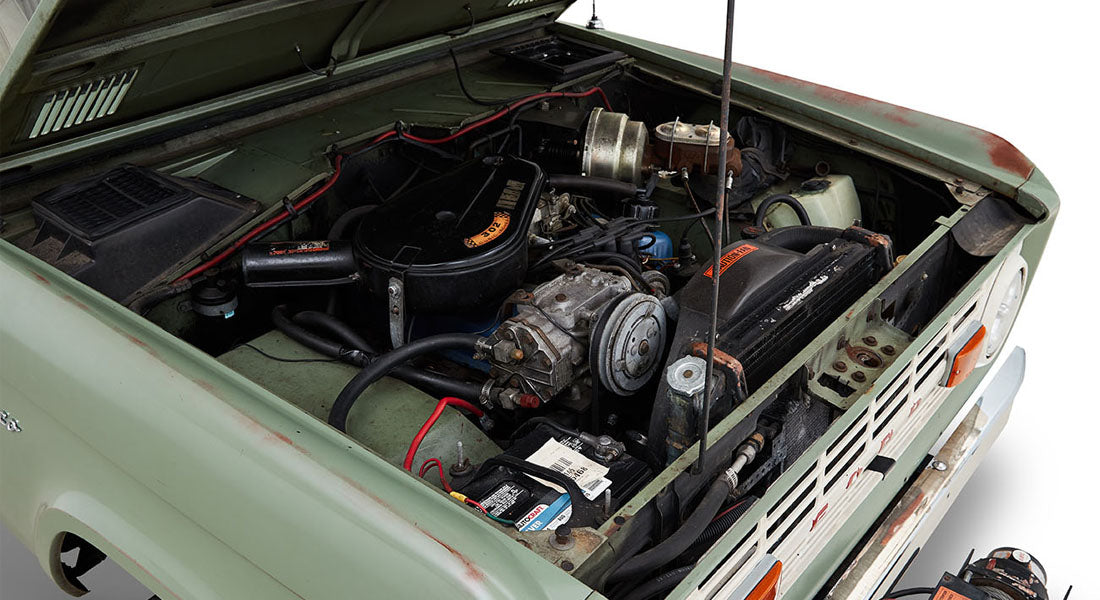 Open hood showing engine compartment of a Classic Ford Bronco with various components