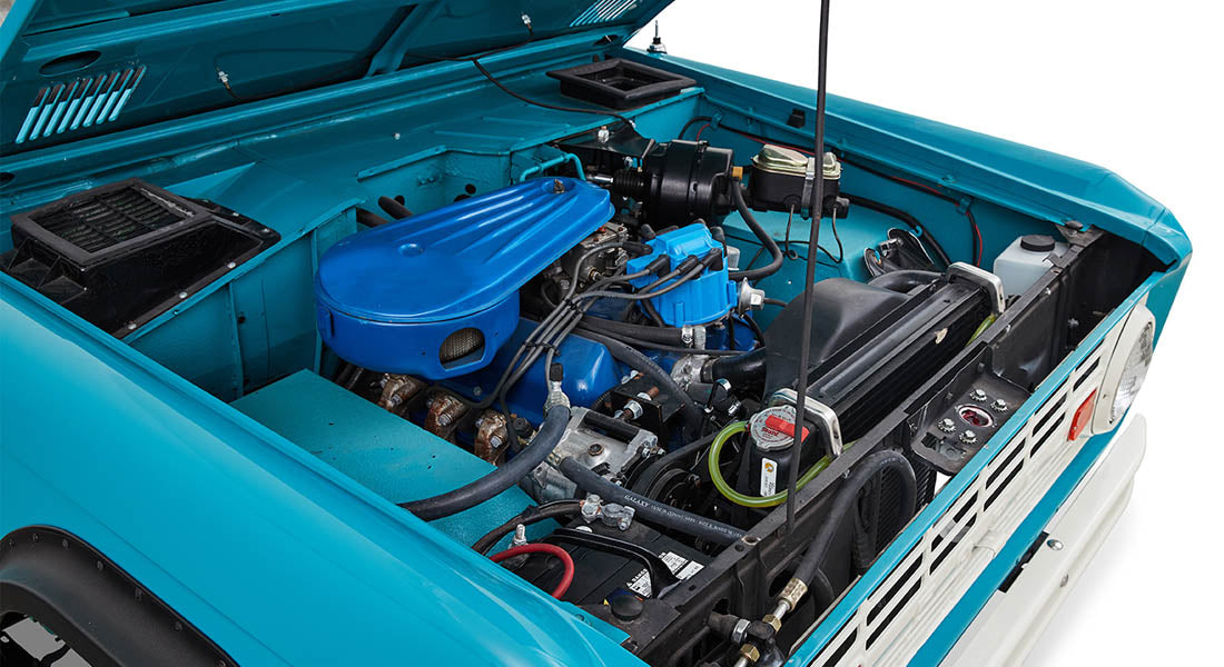 Open hood showing blue engine and components in Classic Ford Bronco engine bay