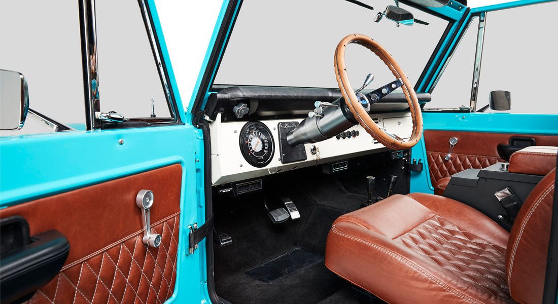 Classic Ford Bronco pedals and footwell area with black carpeting and silver accelerator pedal
